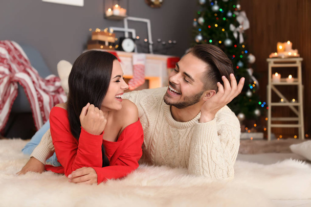 Happy young couple lying on floor at home. Christmas celebration - 写真・画像
