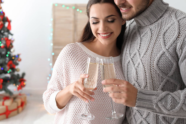 Happy young couple with glasses of champagne celebrating Christmas at home - Fotó, kép