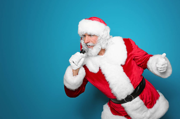 Santa Claus singing into microphone on color background. Christmas music - Фото, зображення
