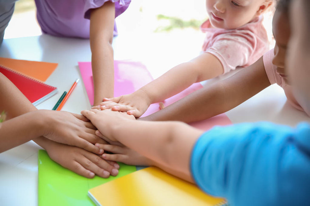 Little children putting their hands together at table, closeup. Unity concept - Photo, image