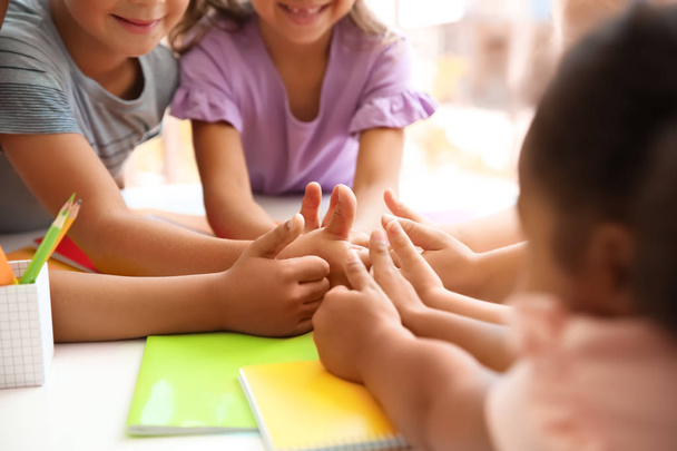 Little children putting their hands together at table, closeup. Unity concept - Fotoğraf, Görsel