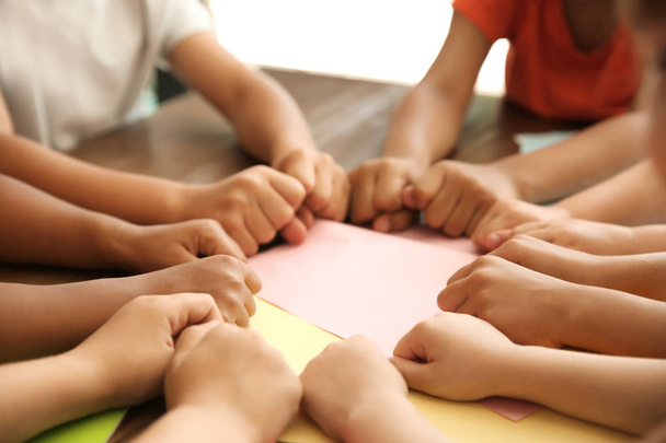 Little children putting their hands together at table, closeup. Unity concept - Photo, Image