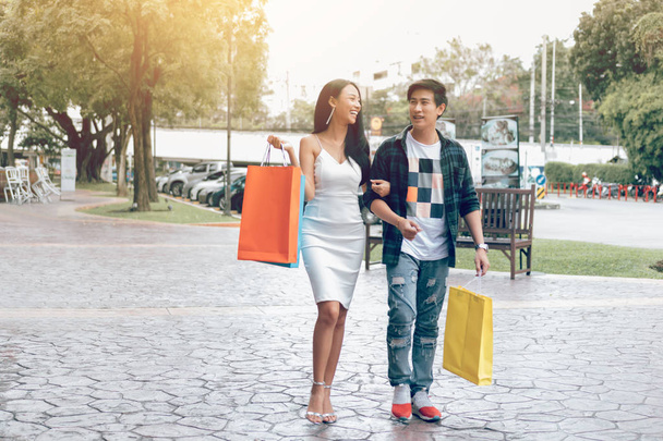 asiatisches Paar läuft auf Straße und hält Einkaufstüten. - Foto, Bild
