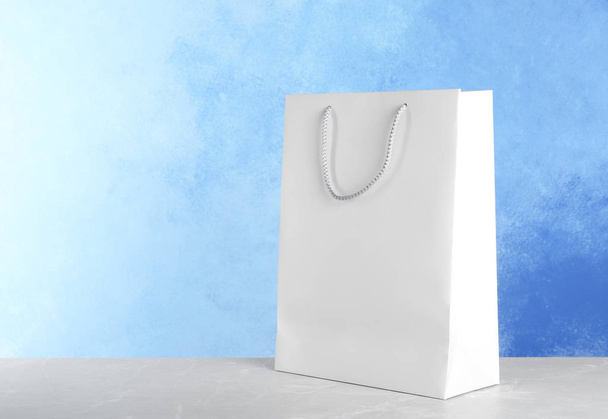 Mockup of paper shopping bag on table against color background - Foto, Bild