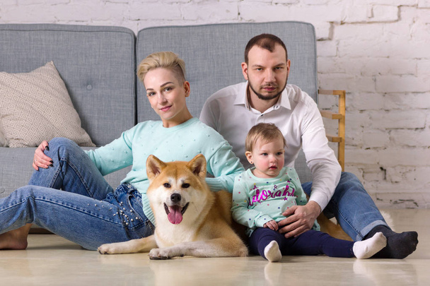 Beautiful young family with little girl and dog sits on floor - Foto, imagen
