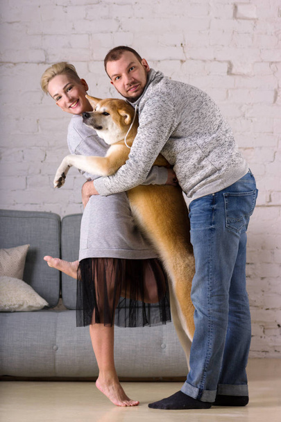 Bella giovane famiglia con cane stand in abbracci
 - Foto, immagini