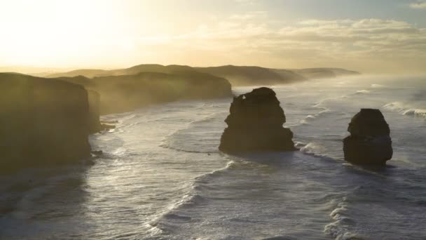 Aamulla auringonnousu yli kalkkikiven kallioita valtameren aallot ja offshore rock pinot Kaksitoista apostolien rantaviivaa Victoria Australia
 - Materiaali, video