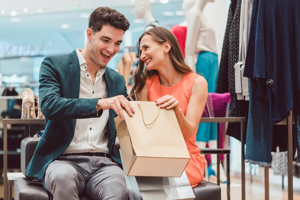 Жінка показує чоловікові те, що вона купила в модному магазині
 - Фото, зображення