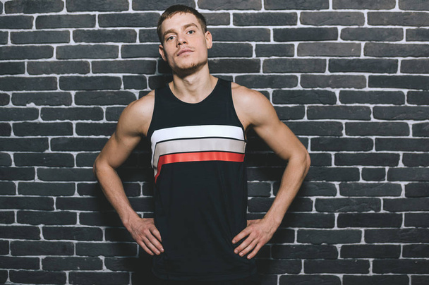 Handsome sportsman resting after training at the gym posing against the wall with copyspace for your text or advertising. Sport, healthy, lifestyle and people concept. - Fotó, kép