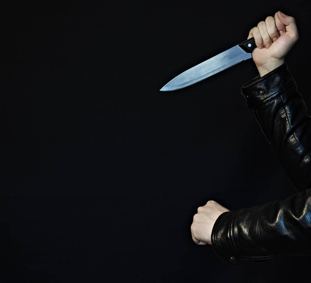 Male hands with a knife and fist on a black background, close-up - Фото, зображення