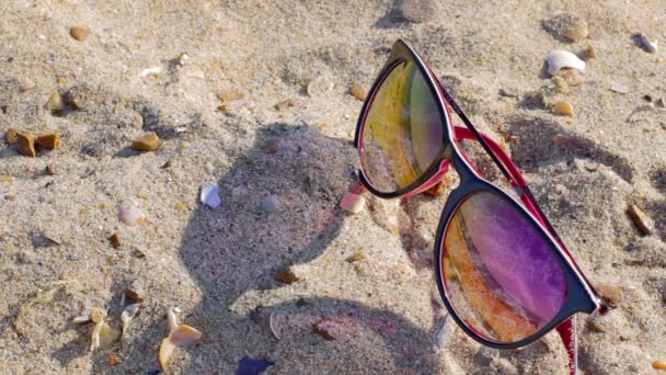 Sunglasses on a sandy beach reflect the sea - Footage, Video