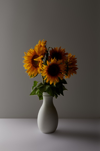 decorative bouquet of yellow sunflowers in vase, on grey - 写真・画像