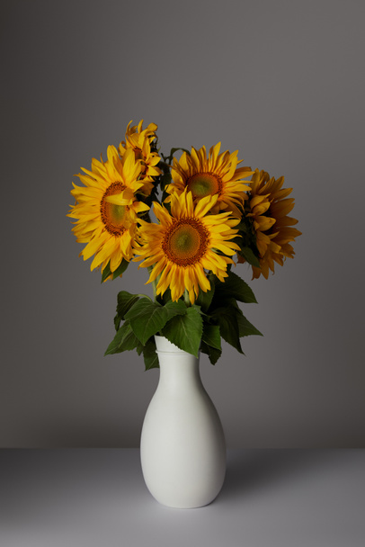 beautiful bouquet of yellow sunflowers in vase, on grey - Fotó, kép