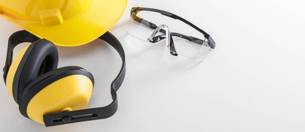 Equipo de seguridad de construcción que incluye sombrero duro, orejeras y gafas protectoras en la imagen del banner de fondo blanco con espacio para copiar
 - Foto, imagen