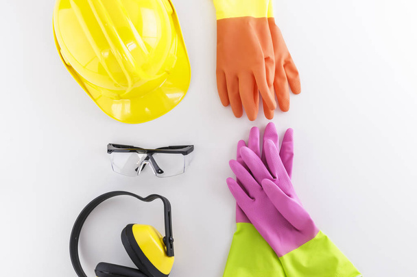 Hard hat, safety goggles, earmuffs, and two pairs of rubber gloves on white background - Photo, Image