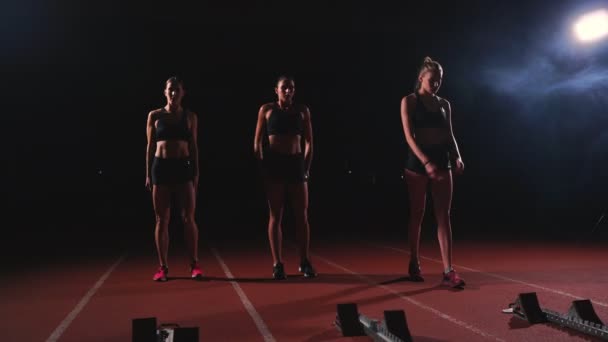 Női futók atlétikai pálya, guggolás: a kezdő blokkok a verseny előtt. A lassú mozgás. - Felvétel, videó