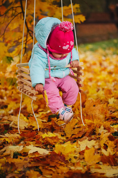 little girl on swings in autumn park - Fotografie, Obrázek