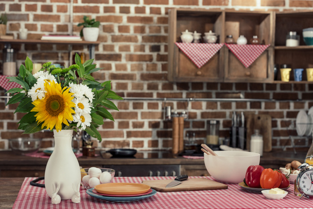 cooking table with flowers bouquet and various products at loft style kitchen - Photo, Image
