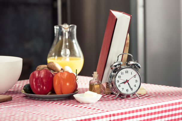 vintage alarm clock with various products and recipe book on table - Φωτογραφία, εικόνα