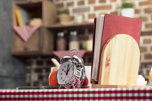recipes book with alarm clock on cooking table at kitchen - Photo, Image
