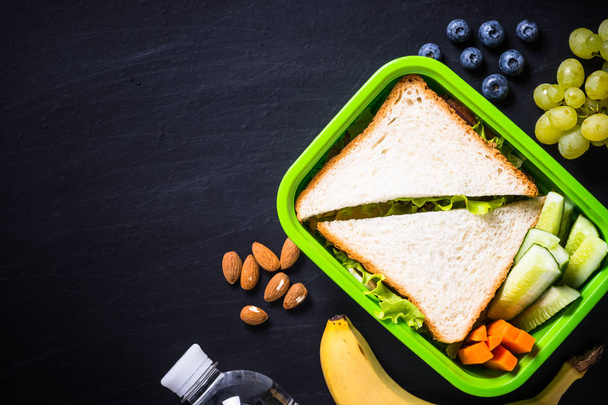 Lunch box with sandwich, vegetables, banana, water, nuts and ber - Photo, Image