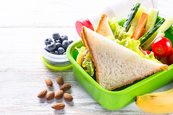 Lunch box with sandwich, vegetables, banana, water, nuts and ber - Photo, Image