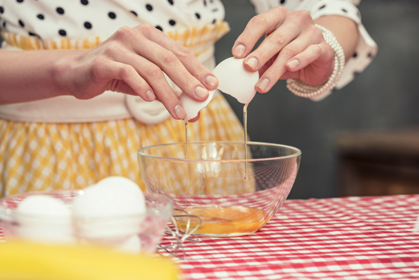 Schnappschuss von Hausfrau im Tupfen-Hemd bricht Ei in Schüssel für Omelett - Foto, Bild