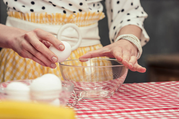 bijgesneden schot van huisvrouw ei breken in kom voor omelet - Foto, afbeelding