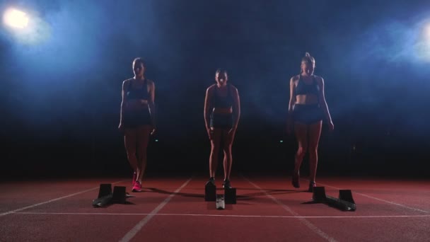 Jonge vrouwelijke loper atleet met smartwatch klaar om te sprinten op hardloopbaan startlijn - Video