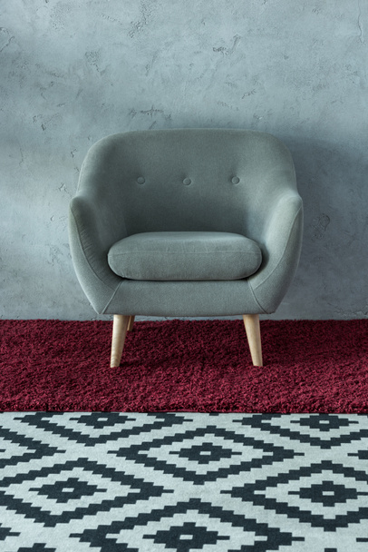 grey armchair on burgundy carpet near grey wall in office - Photo, Image