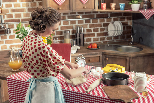 atraente dona de casa adulta preparando massa em tigela de vidro na cozinha
 - Foto, Imagem