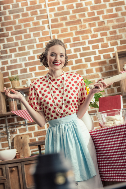счастливая взрослая домохозяйка со скалкой глядя в камеру на кухне
 - Фото, изображение