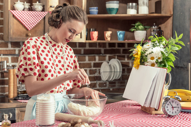 красивая взрослая домохозяйка проливает муку на тесто в миске на кухне
 - Фото, изображение