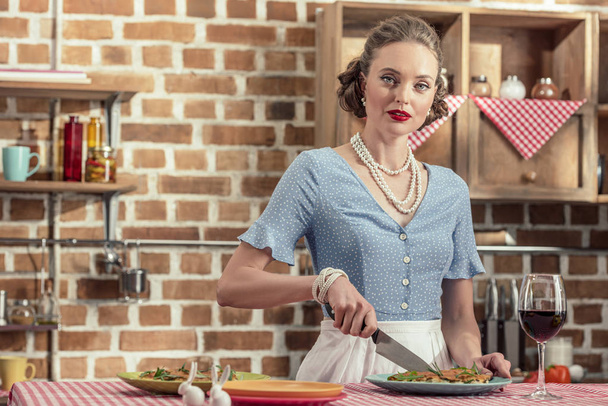 schöne erwachsene Hausfrau schneidet frischen Pilzkuchen und schaut in die Küche - Foto, Bild