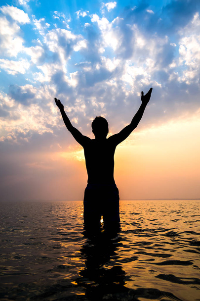 Happy Man sylwetka z rękami w górze w wodzie na tle zachodu słońca - Zdjęcie, obraz
