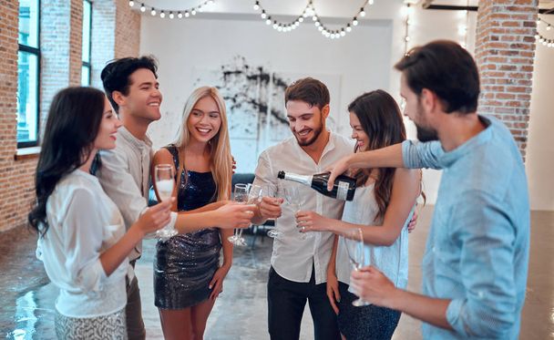 Let the party begin! Group of young people having fun together. Dancing in big light room with champagne. Celebrating holiday in big company of close friends. - Φωτογραφία, εικόνα