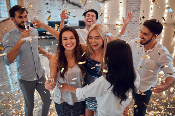 Let the party begin! Group of young people having fun together. Dancing in big light room with champagne and confetti falling. Celebrating holiday in big company of close friends. - Φωτογραφία, εικόνα