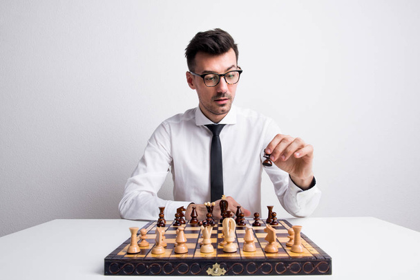Portrait of a young man in a studio, playing chess. - Foto, Imagem