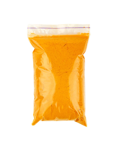 Feche um saco de fecho de correr de plástico cheio de especiarias de açafrão amarelo em pó isolado no fundo branco
 - Foto, Imagem