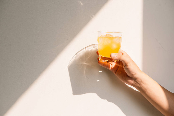 Hand holding full glass of orange juice in the morning in summer - Fotografie, Obrázek
