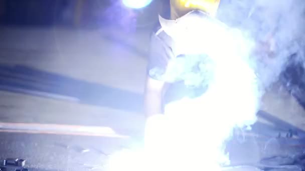 Young engineering career concept. Handsome young engineer in workshop with blowtorch doing arch welding on floor. Chinese man with welding mask in real engineering workshop. Lots of spark and flash. - Footage, Video