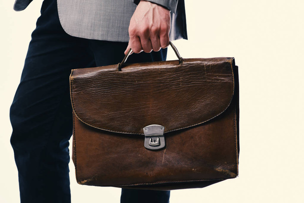 Male hand holds brown leather bag. Working style and classic fashion. Man with briefcase isolated on white background. - Foto, Bild