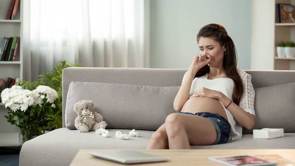 Upset pregnant lady crying on sofa, hormonal disorder emotional problems - 写真・画像