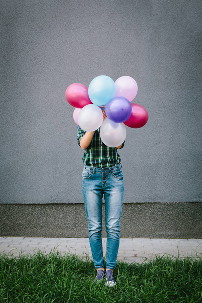 Молодая женщина прячется за красочными воздушными шарами
 - Фото, изображение