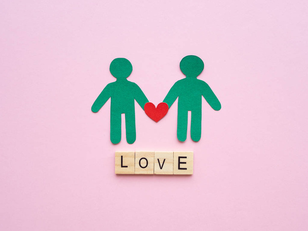 Mies pari paperi punaisella sydämellä ja LOVE teksti puinen lohko vaaleanpunainen tausta. Rakkaus, LGBT, homo ylpeys, homoseksuaali, Ystävänpäivä käsite
. - Valokuva, kuva
