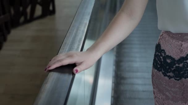 femme monte sur un escalier roulant tenant sur une rampe
 - Séquence, vidéo
