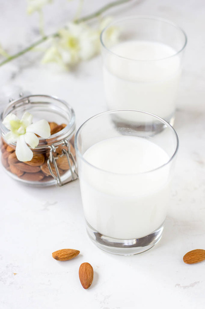 Мигдальне молоко в склянці на білому тлі. Органічне веганське молоко
. - Фото, зображення