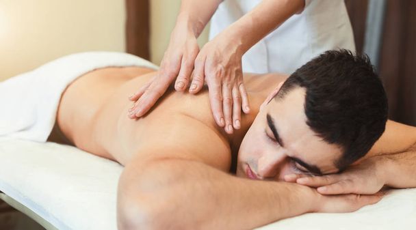 Portrait of handsome man receiving back massage - Фото, изображение