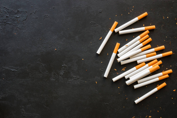 Cigarettes and tobacco on a black background with space for text - Foto, Bild