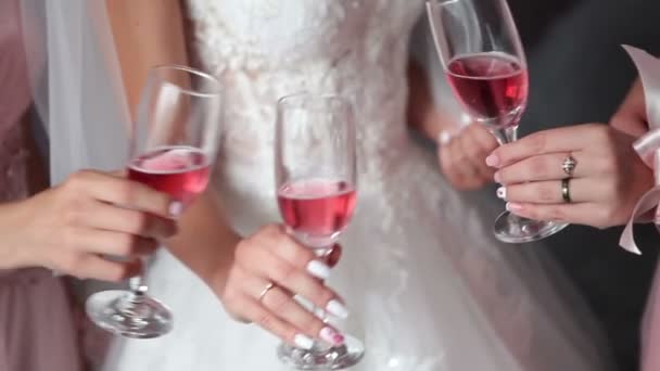 La sposa e le sue amiche reggono bicchieri con champagne rosa. Vino rosato in bicchieri da sposa. Le ragazze vogliono bere vino rosa. La sposa sta bevendo champagne rosa con le ragazze.
. - Filmati, video